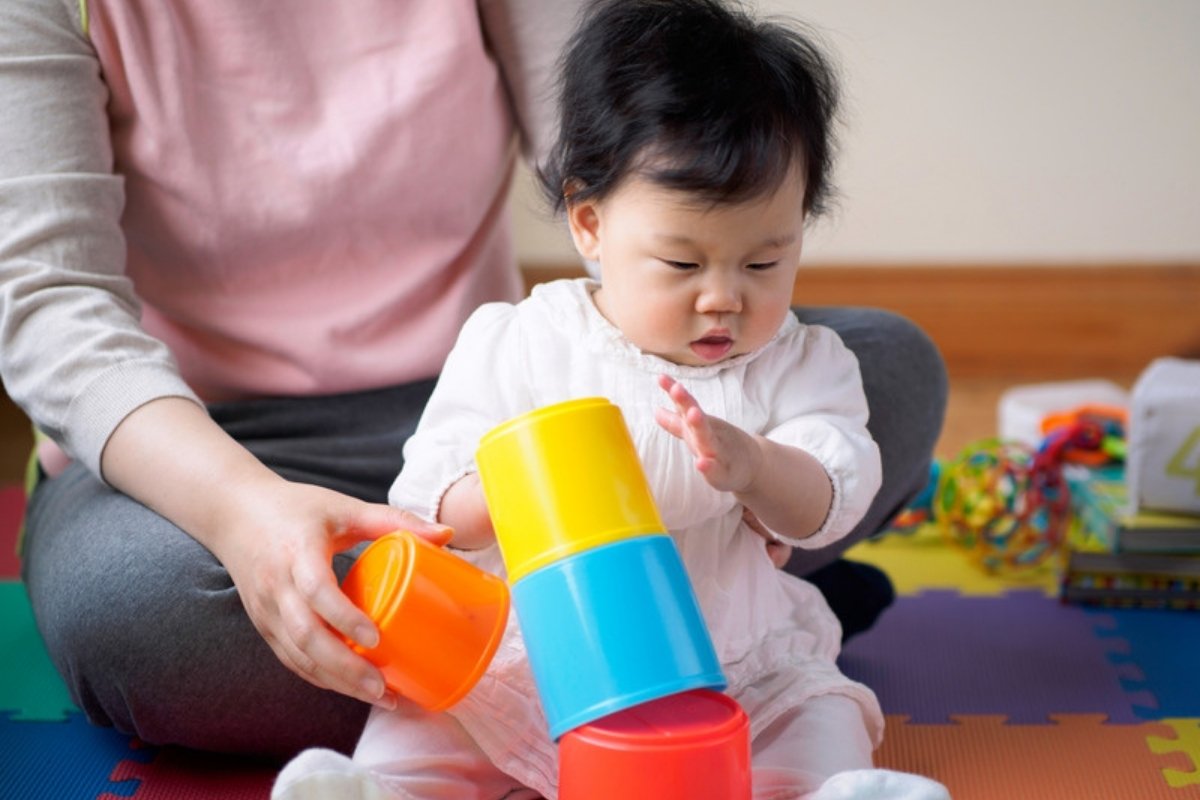 Baby girl stacking colorful cups with her mom