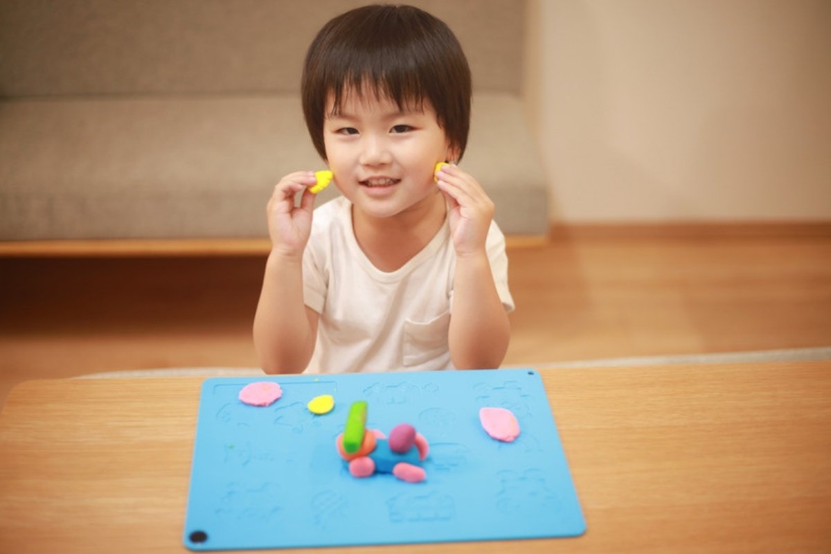 Toddler boy playing with play dough at a table