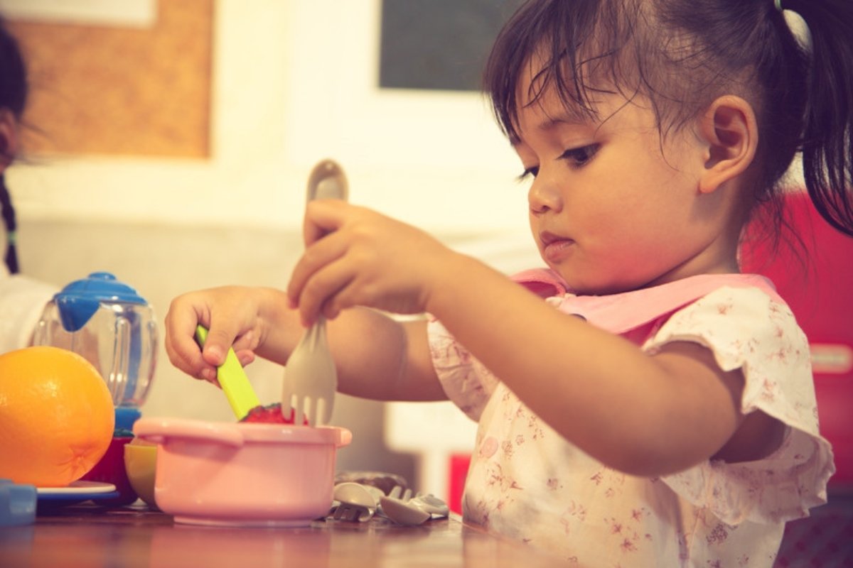 Little girl cutting toy food in pretend play
