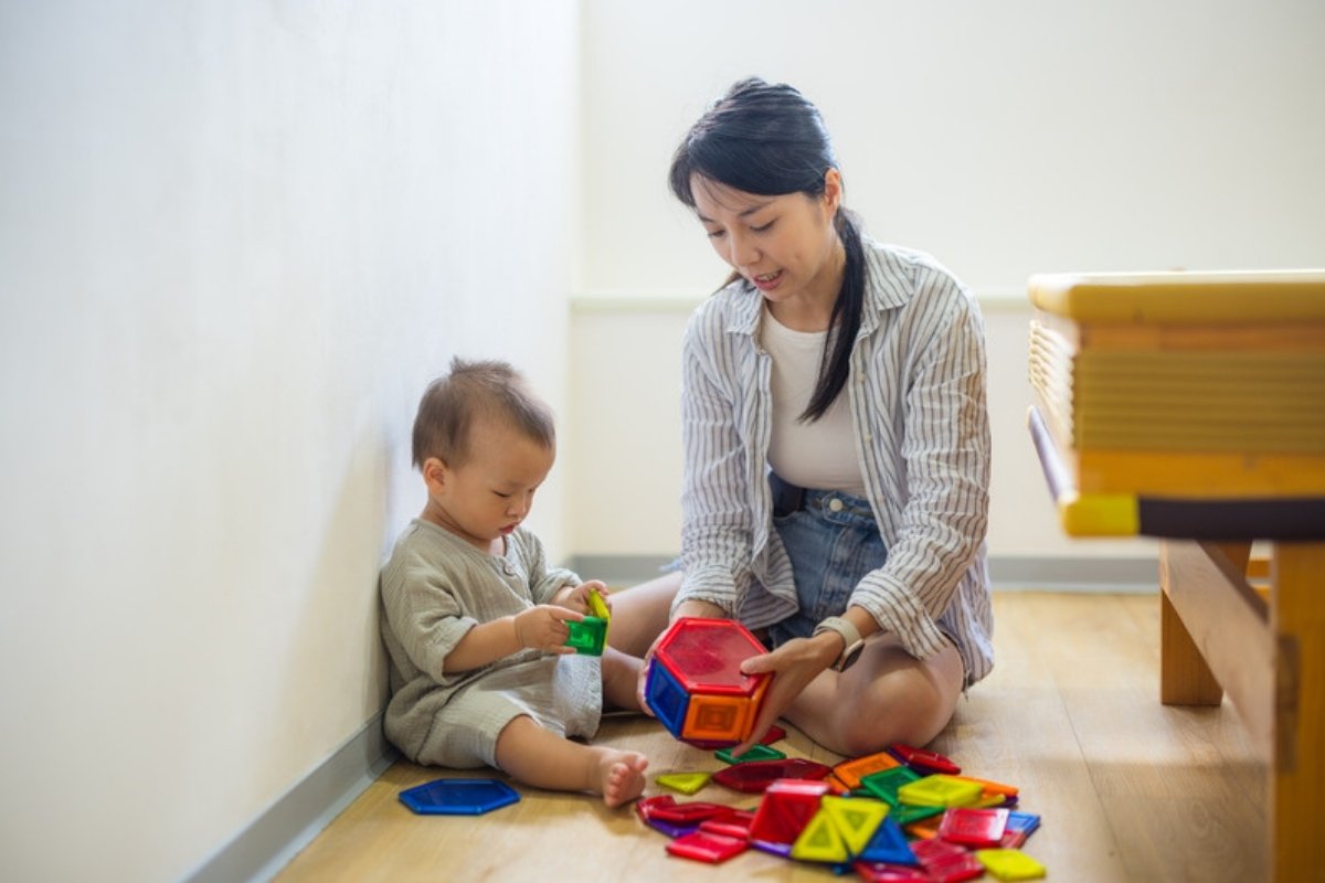 Mom and toddler building with colorful magnetic tiles