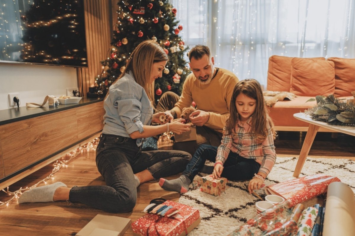 Family wrapping Christmas presents together on the living room floor
